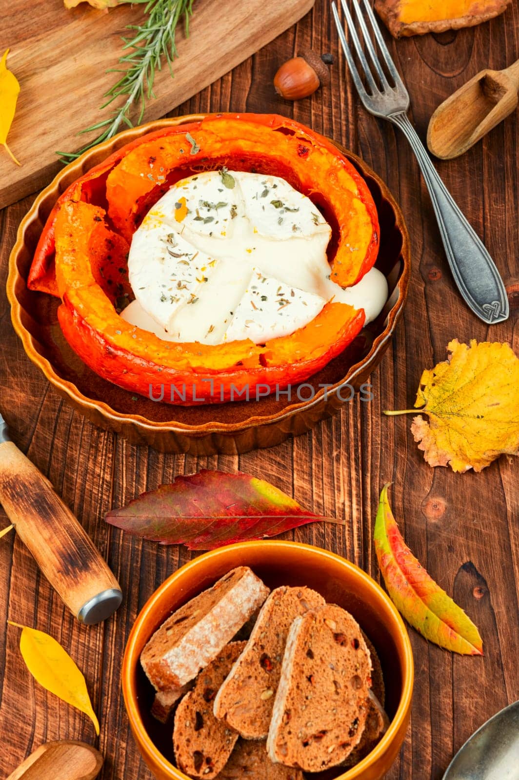 Delicious baked pumpkin with camembert cheese on a rustic wooden table. Dietary food.