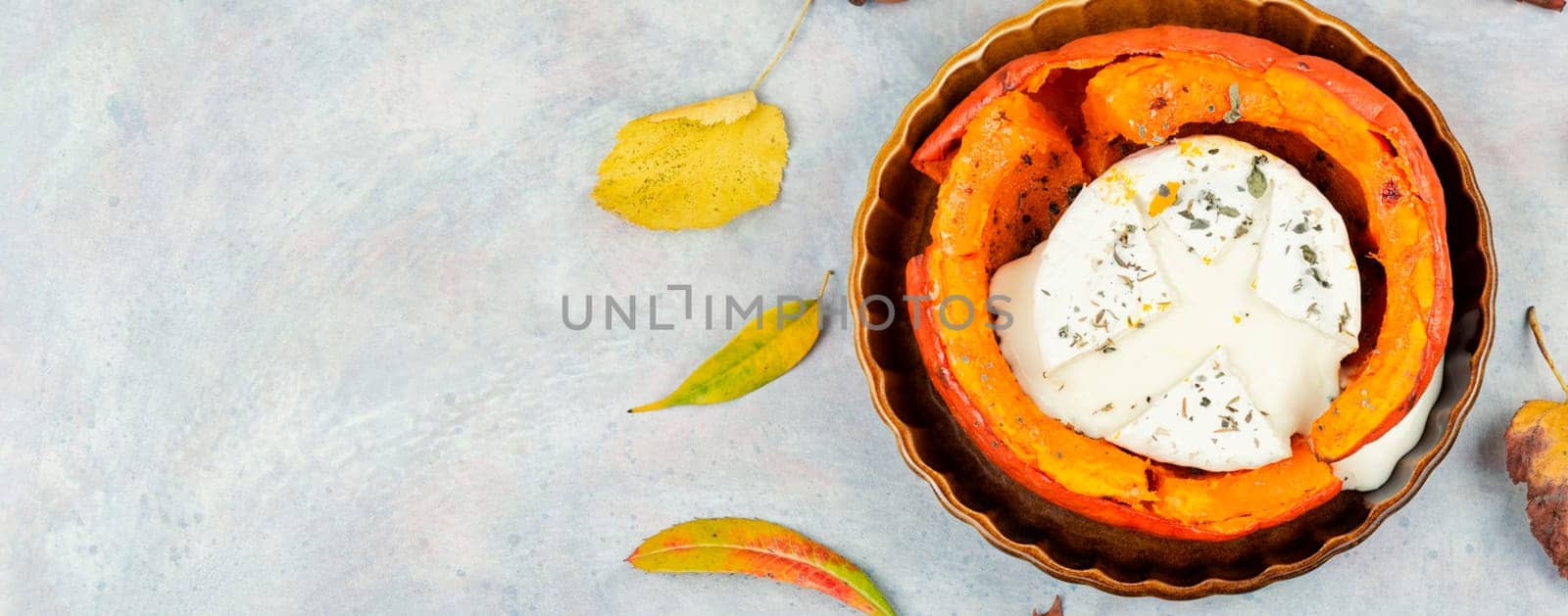 Delicious baked pumpkin with camembert cheese on a rustic wooden table. Dietary food.