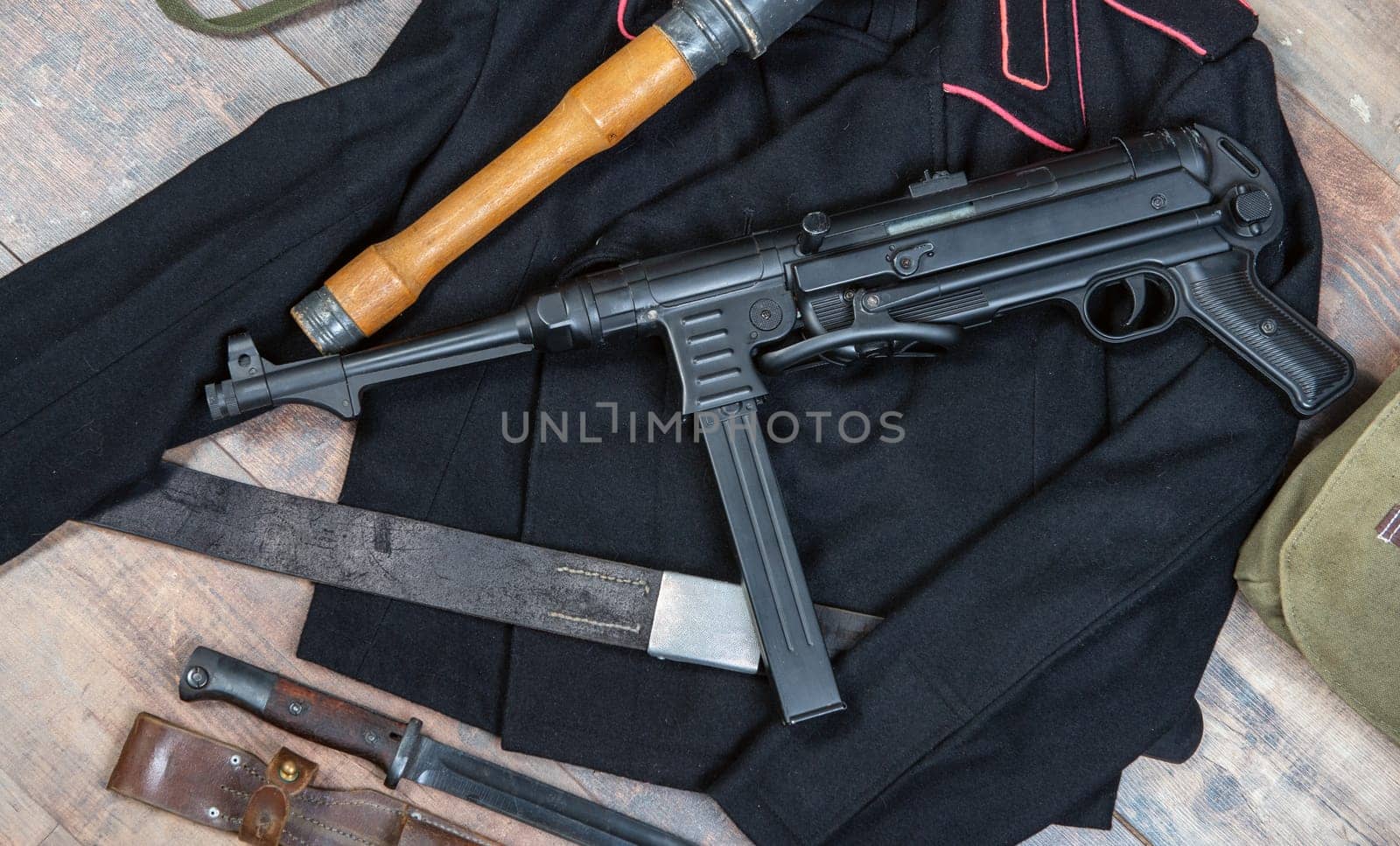 A german machine gun is on a table next to a knife. Scene is tense and ominous