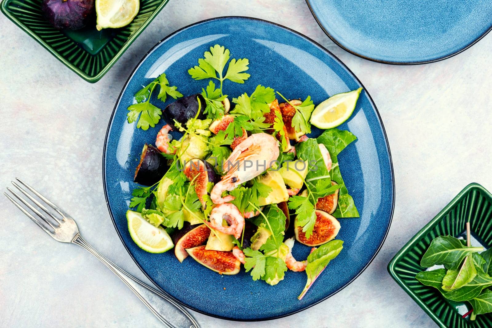 Platter of green salad with figs and figs. Seafood salad on a concrete kitchen table.