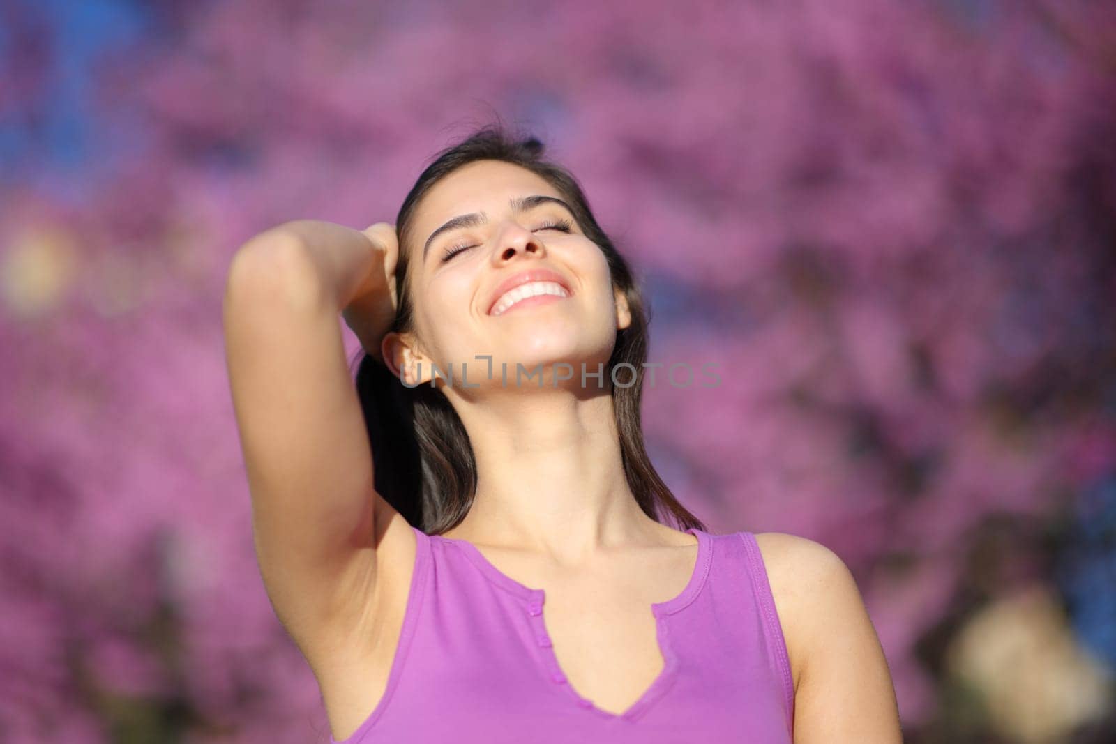 Happy woman smiling and touching hair in a violet park