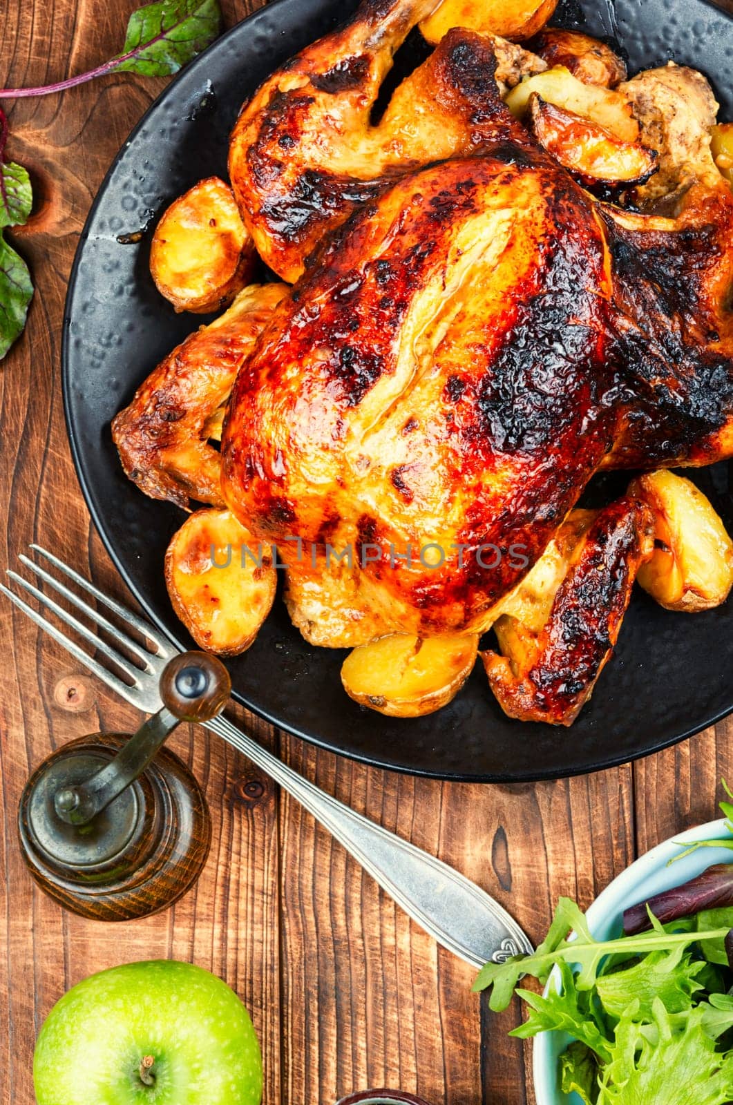Baked chicken with vegetables and apples on rustic wooden table. Grilled poultry.
