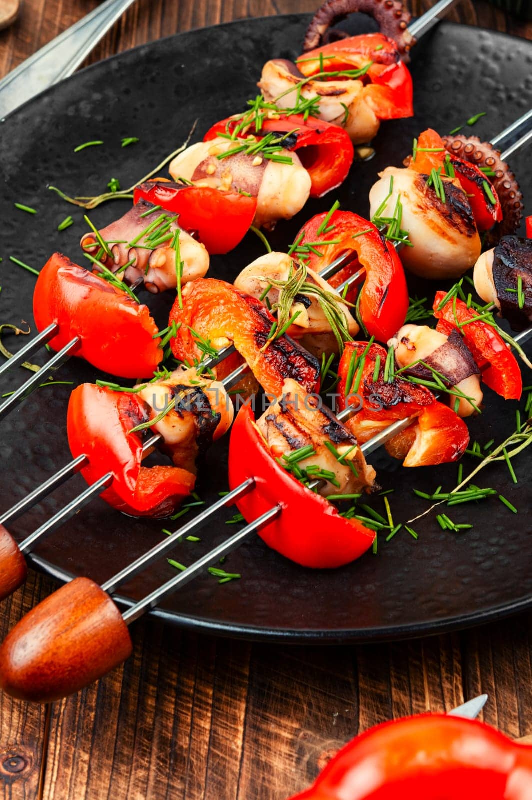 Succulent grilled octopus tentacles with bell pepper on a concrete kitchen table.