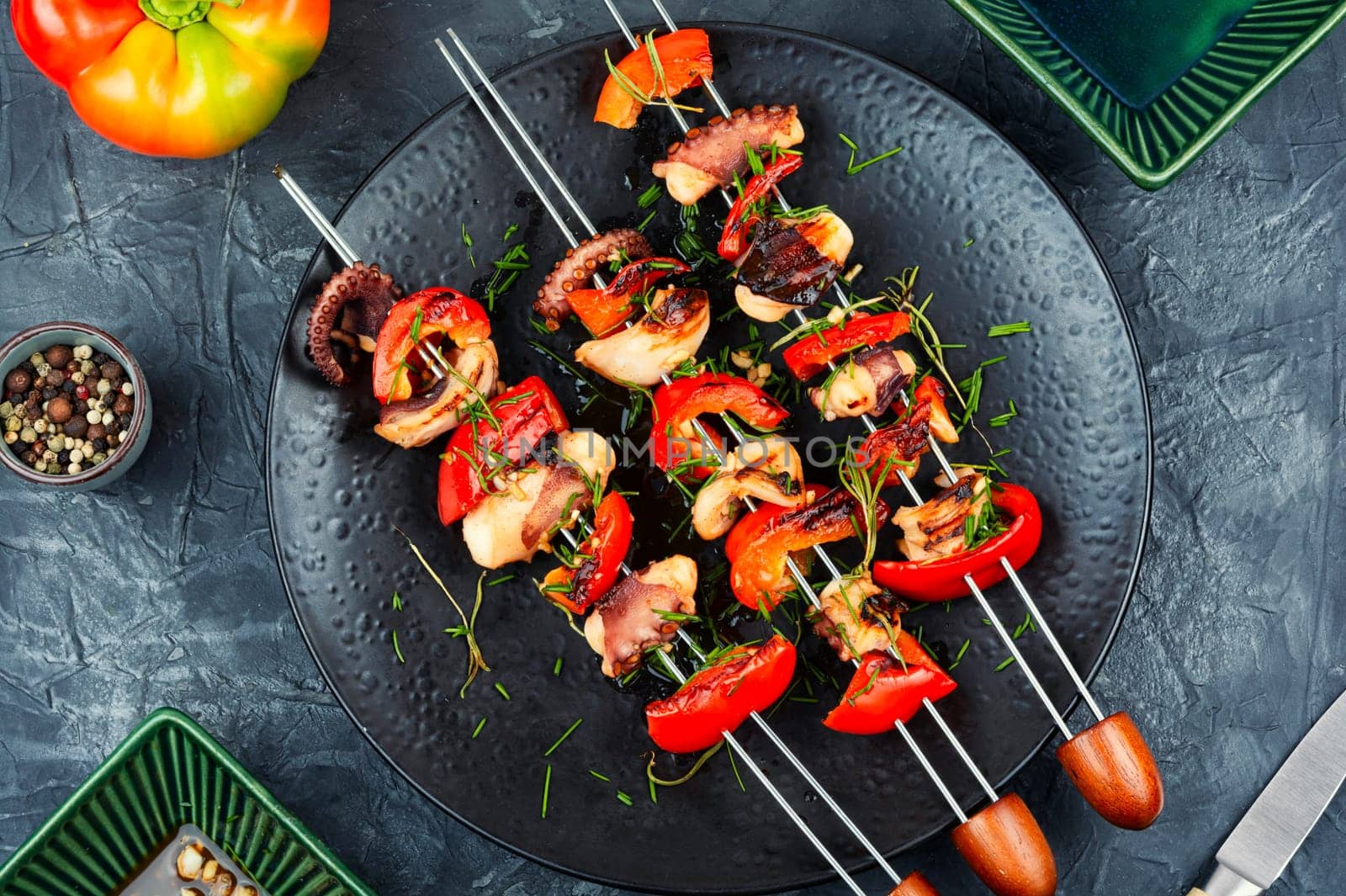 Succulent grilled octopus tentacles with bell pepper on a concrete kitchen table.