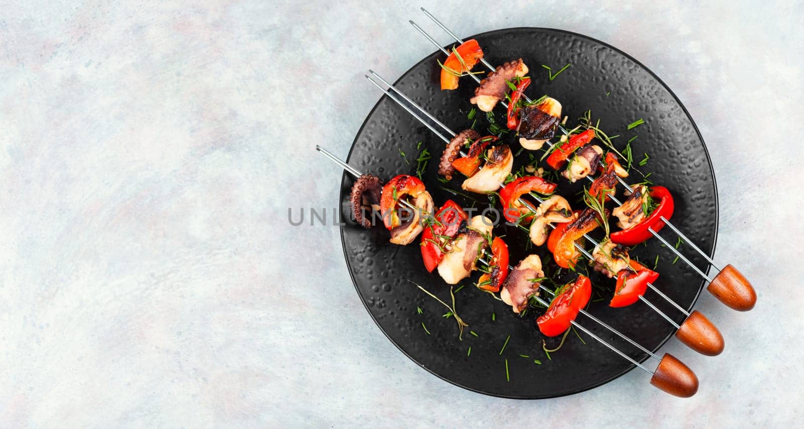 Succulent grilled octopus tentacles with bell pepper on a concrete kitchen table.