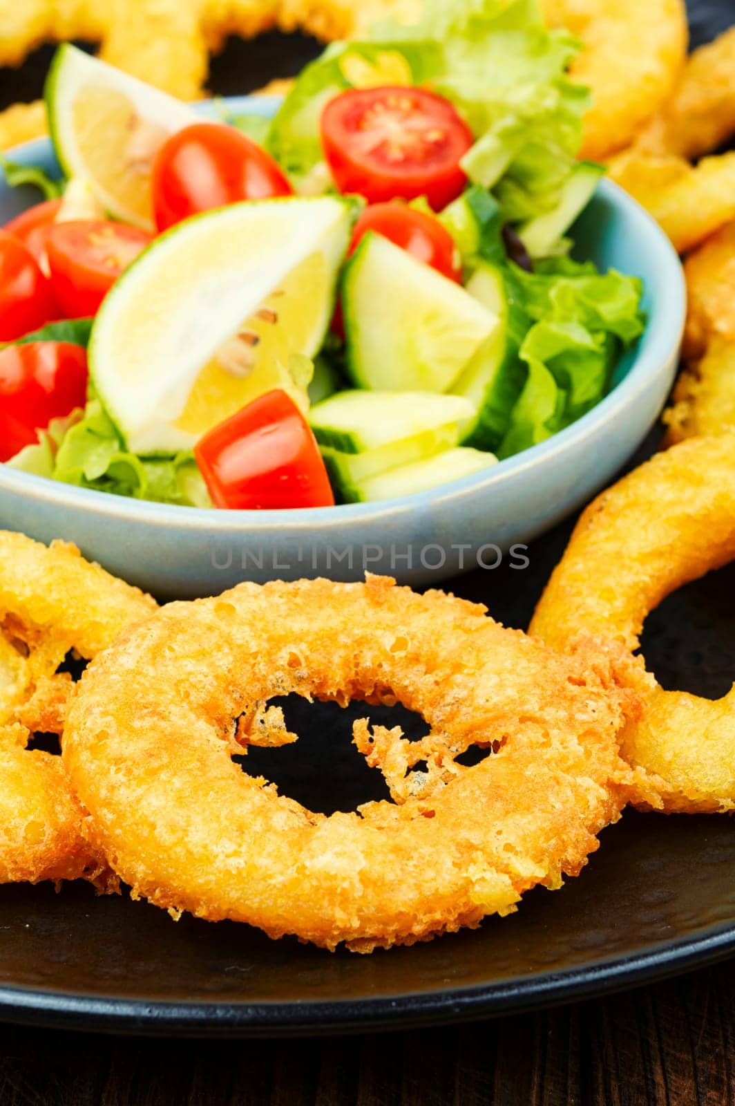 Delicious Fried squid rings and fresh vegetable salad. Close up.