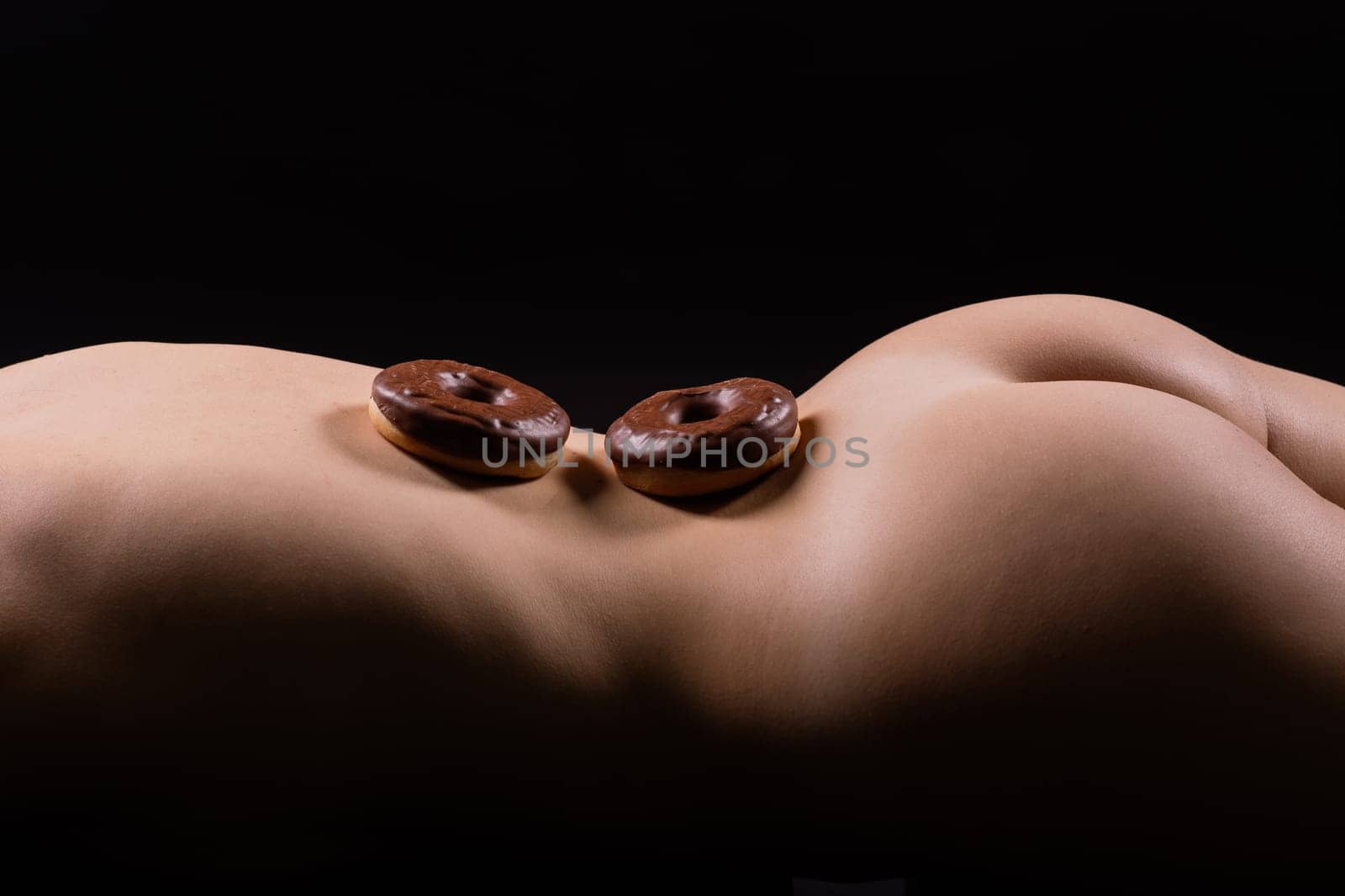 Plus size seductive model female, fashionable blonde in a black bodysuit with donut