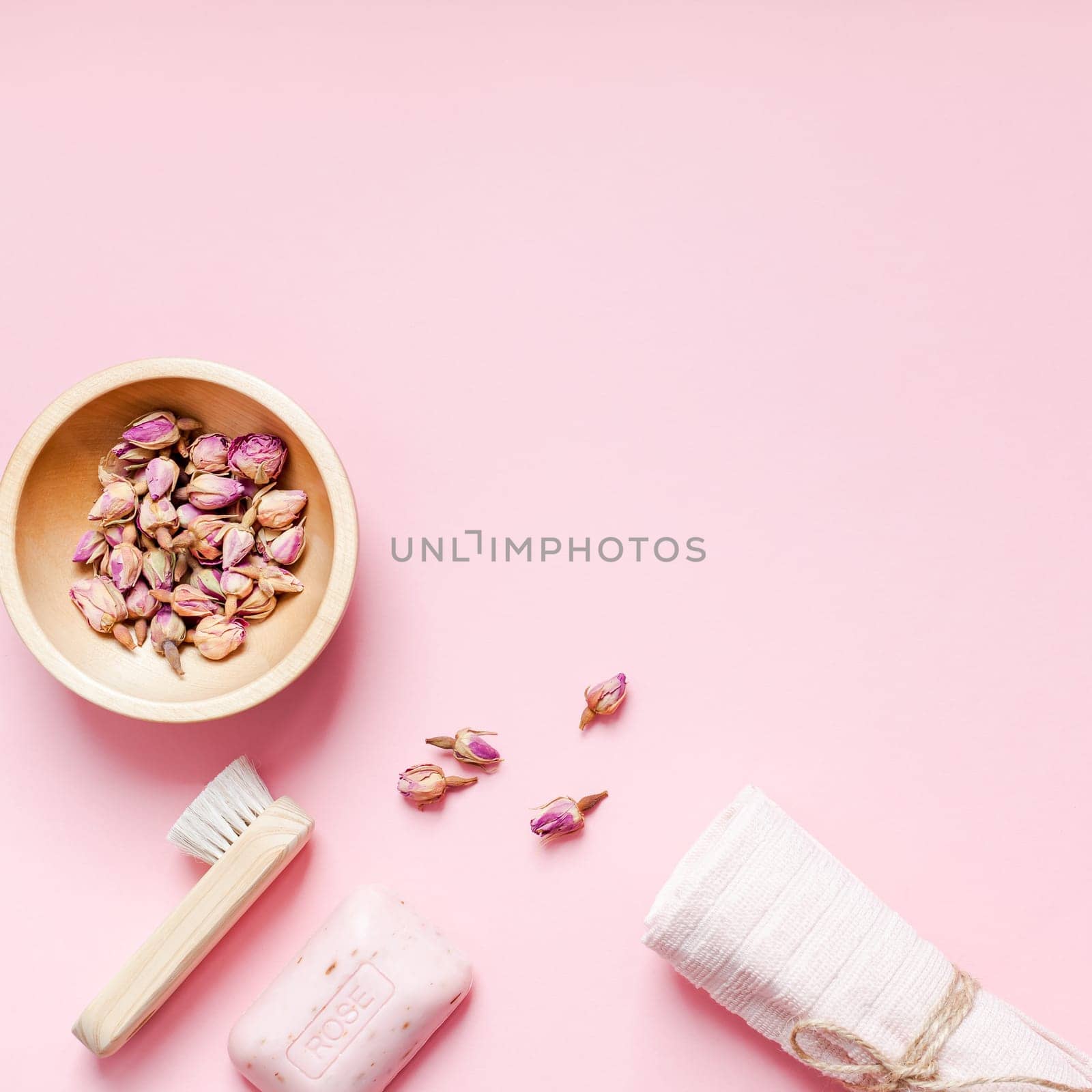 Spa, beauty cosmetics and body care treatment concept with copy space. Creative top view flat lay composition with bath accessories, organic DIY rose soap and dry flowers in a bowl on pink background