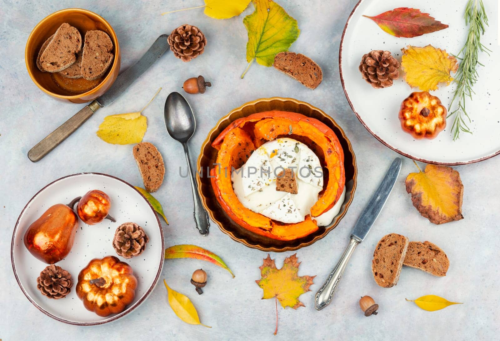 Autumn pumpkin baked with camembert cheese on a rustic wooden table. Healthy food.