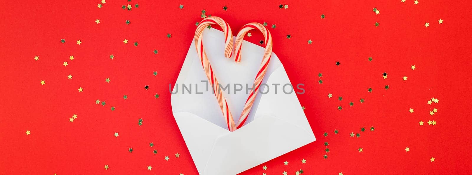 New Year or Christmas decoration flat lay top view Xmas holiday celebration handmade decor sweets golden stars glitter on red paper background. Template frame long wide banner