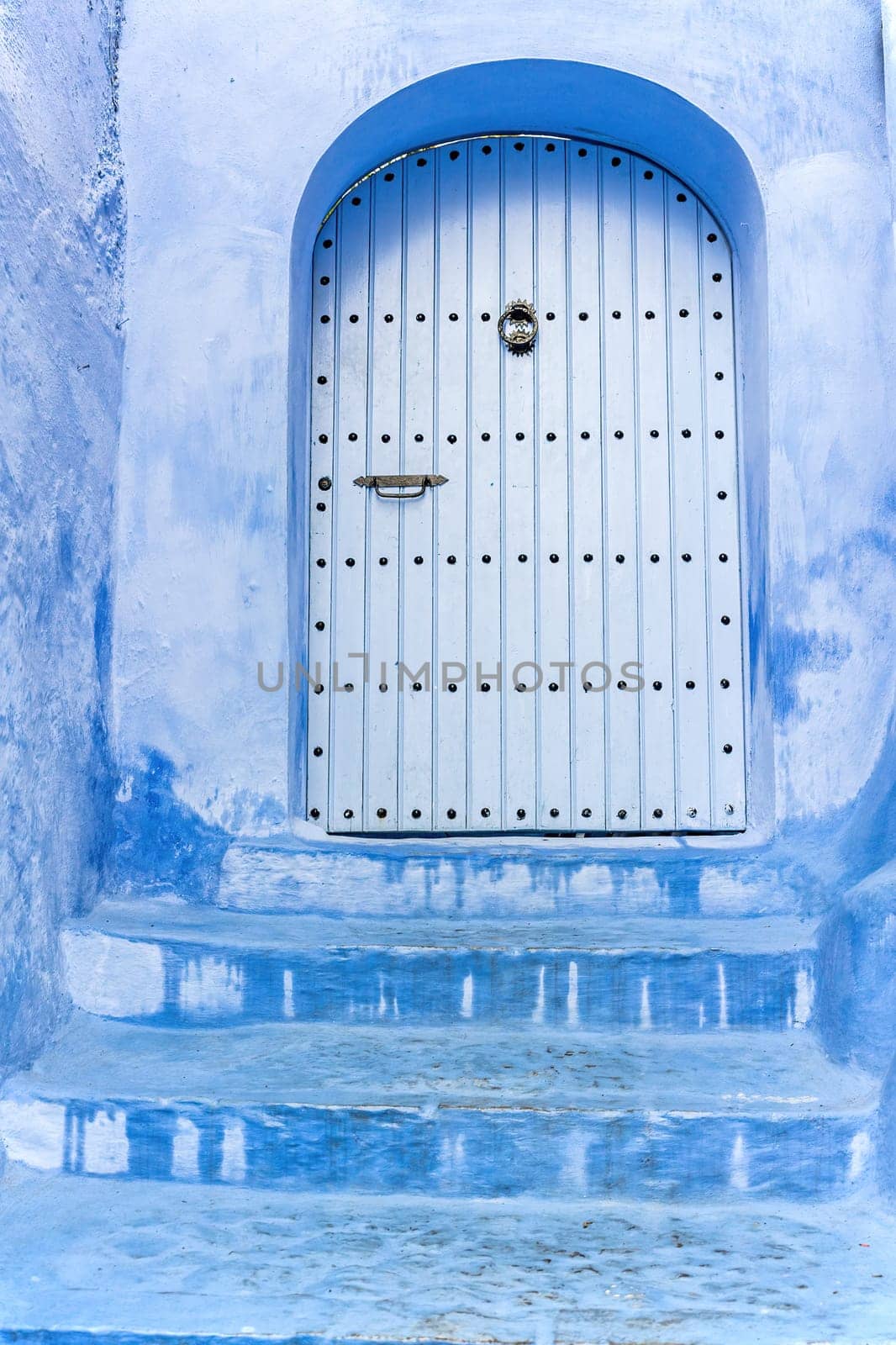 Blue stairs leading to an azure blue door in the city of Chefchaouen closeup.  Morocco. Vertically.