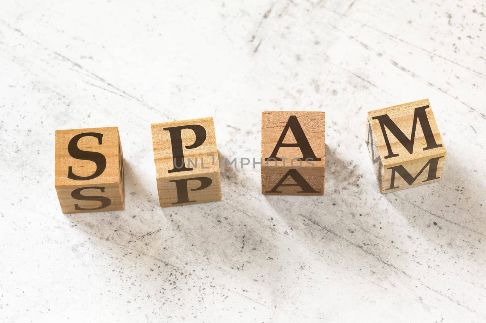 Four wooden cubes with word SPAM on white working board.