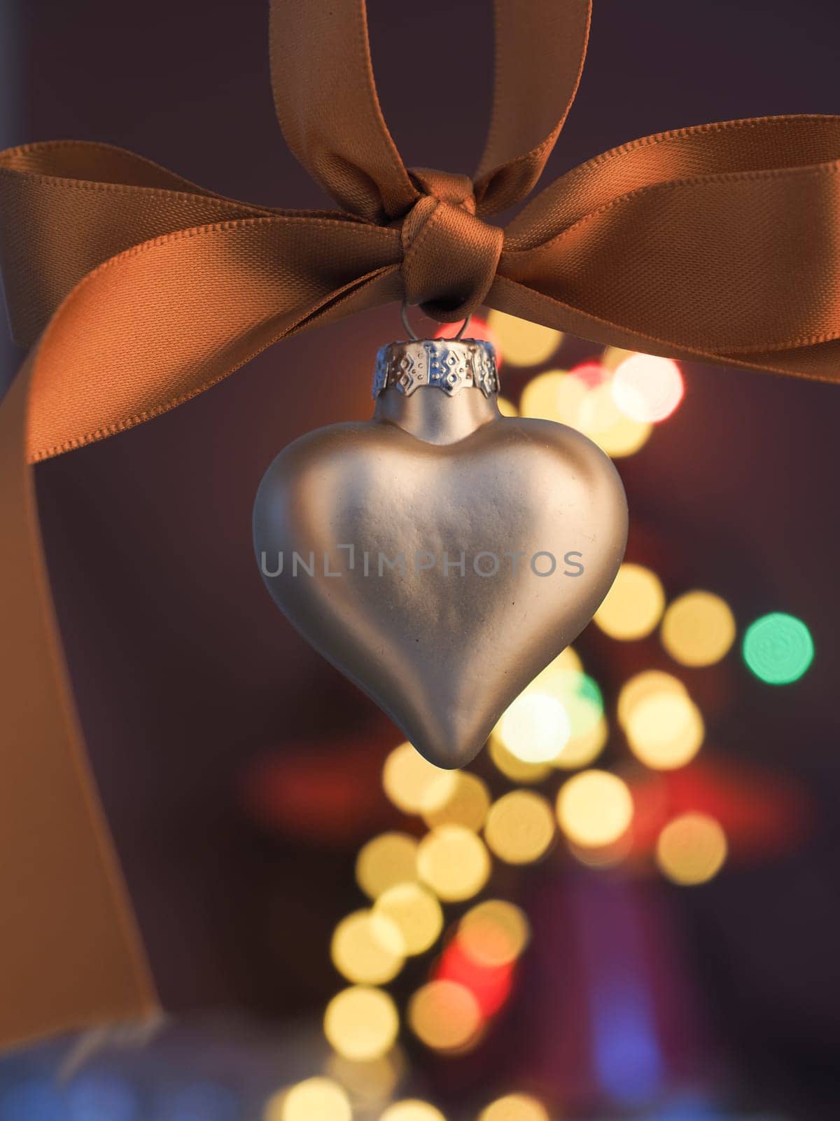 Silver heart shaped Christmas bauble on a blurred Christmas lights background