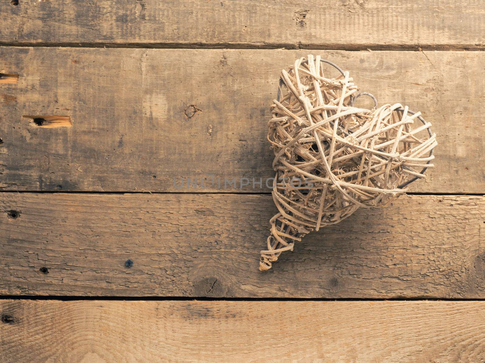 A woven heart shape on a rustic wooden background with space for your text or image