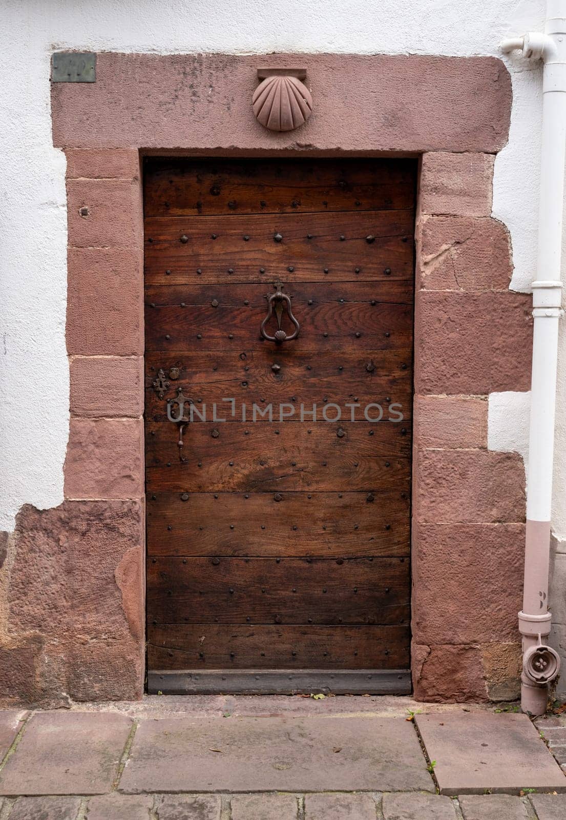 A wooden door with a shell-shaped knob. The door is located in front of a stone wall