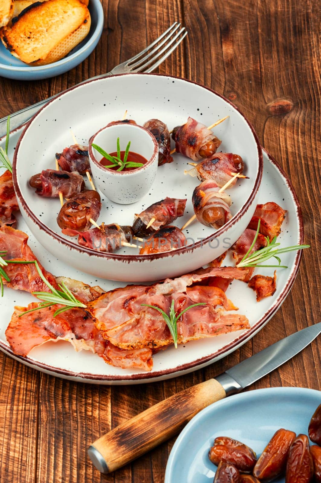 Homemade sweet and savory bacon wrapped dates served on a platter. Rustic style.