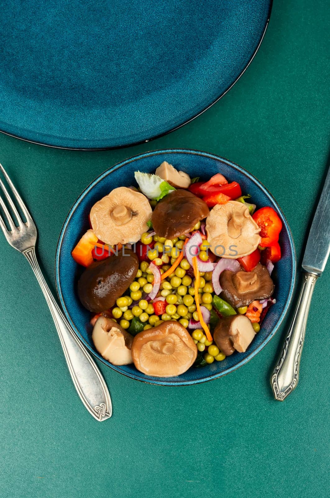 Dietary vegetable salad with marinated pickled mushrooms, green peas in bowl. Space for text.