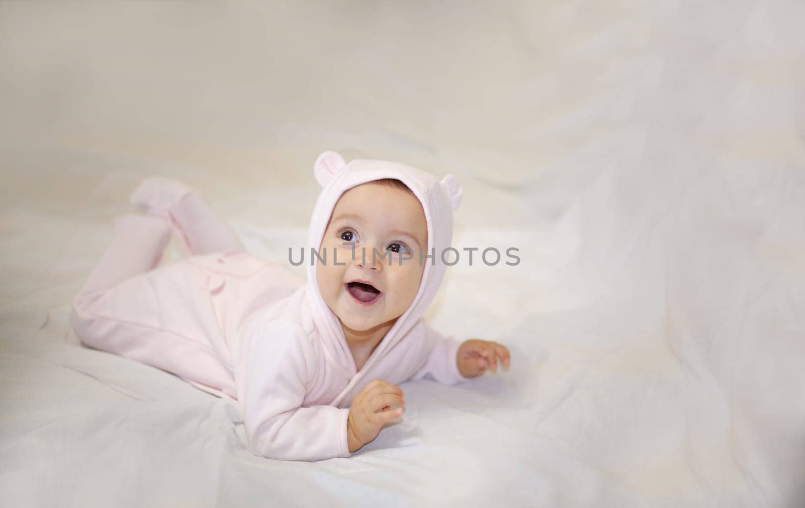 An adorable baby is smiling brightly while wearing a cozy pink outfit, ideal for capturing heartwarming moments