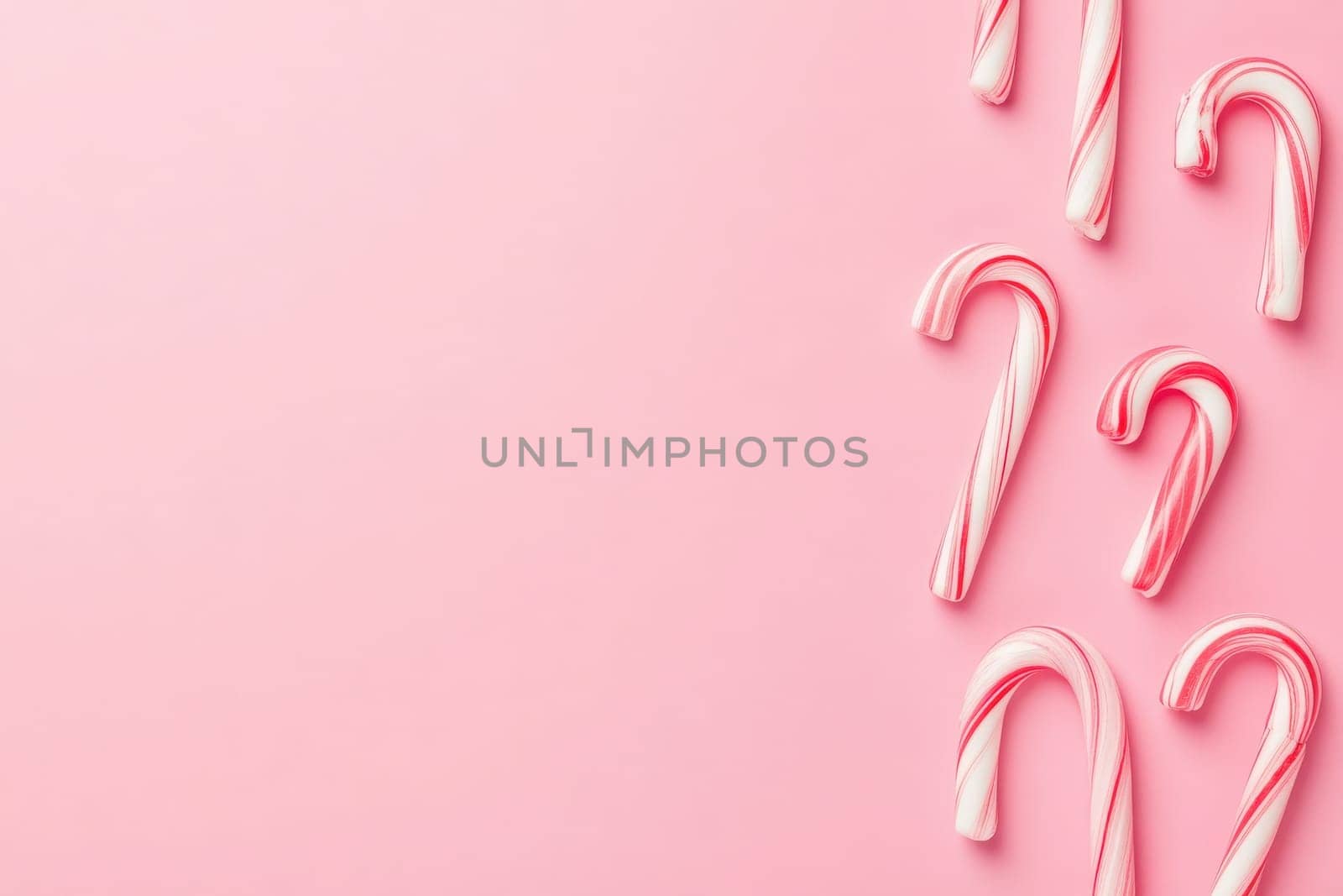 A collection of colorful candy canes is displayed against a soft pink backdrop, evoking a festive and joyful atmosphere perfect for holiday celebrations and sweet treats.