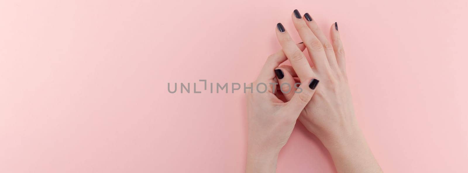 Stylish trendy female black manicure. Beautiful young woman's hands on millennial pink pastel background. Beauty and SPA concept. Banner Template for feminine blog social media