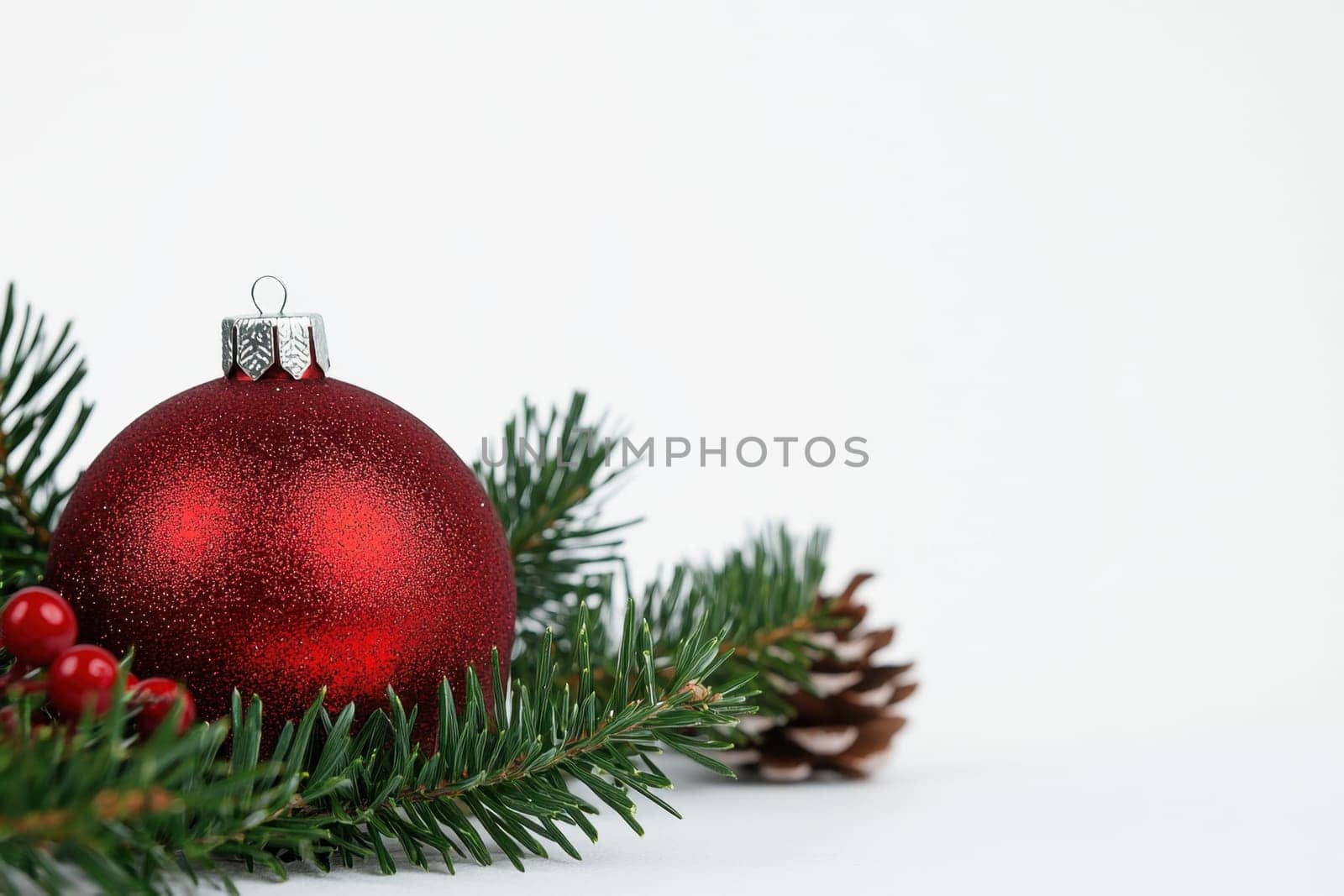 Bright red ornament rests among evergreen branches and pine cones capturing the spirit of the Christmas season with natural decorations.