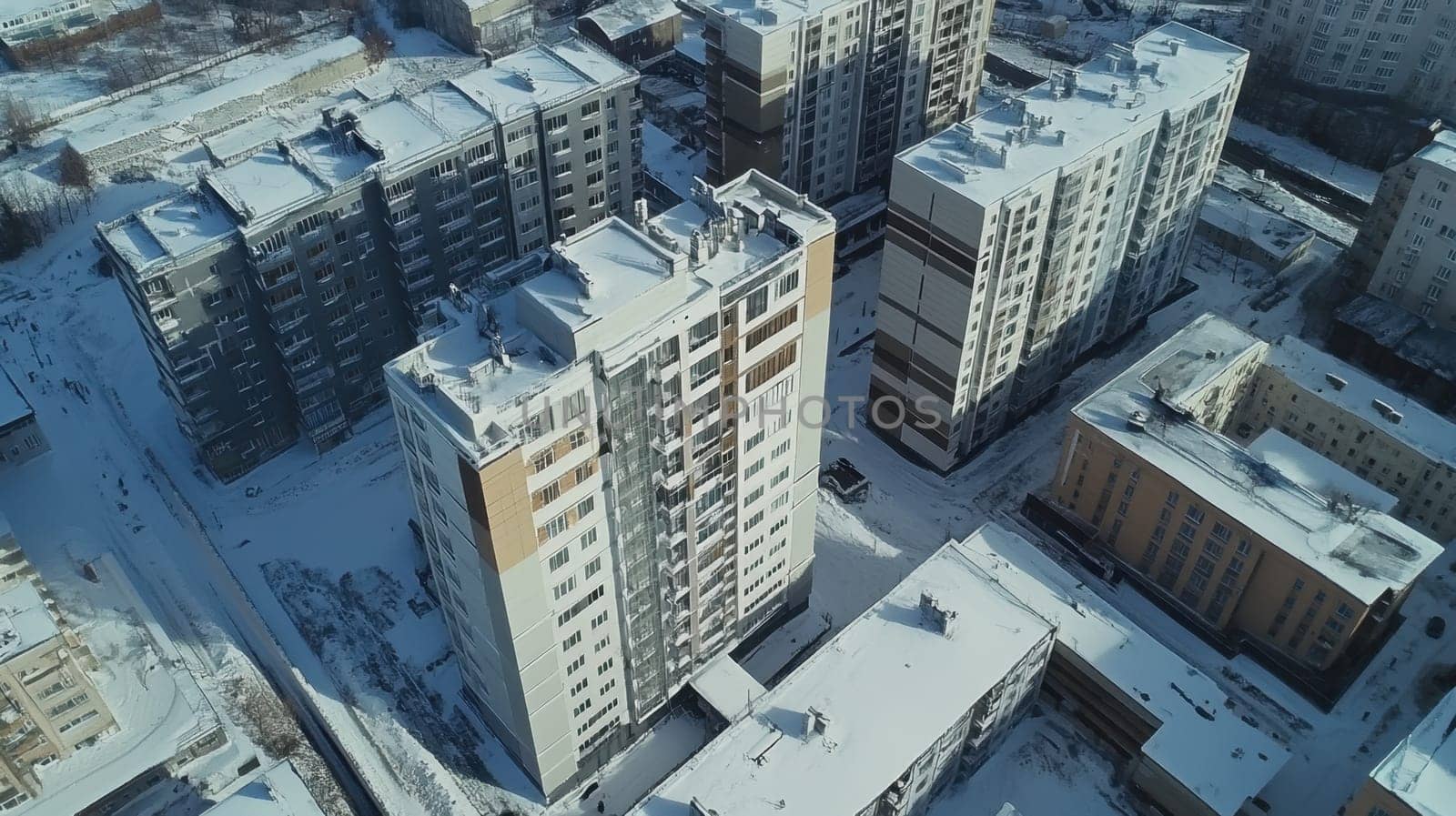 Aerial view of snow covered residential buildings during a winter sunset showcasing urban architecture blanketed in white.