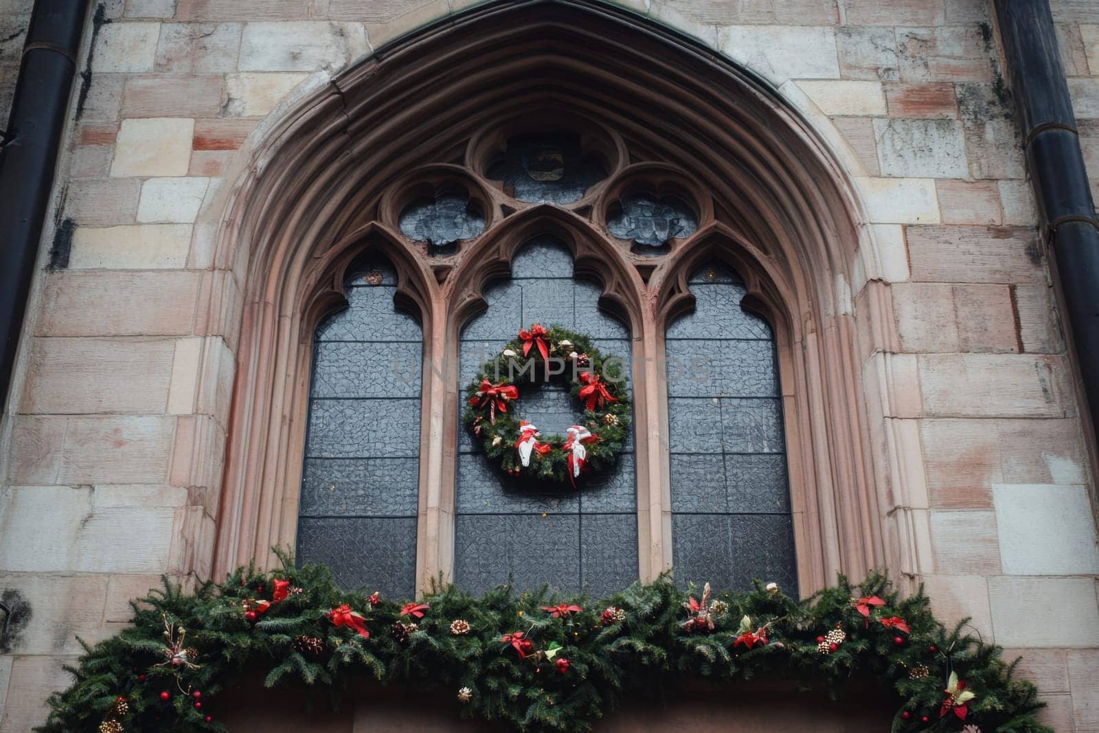 A beautiful wreath adorned with red ribbons hangs on a church window surrounded by lush greenery capturing the festive spirit of the season.