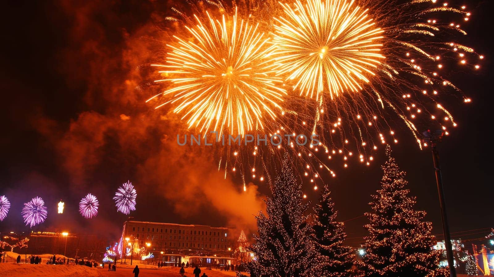 Colorful fireworks burst over a festive winter celebration lighting up the night sky and surrounding trees filled with snow.
