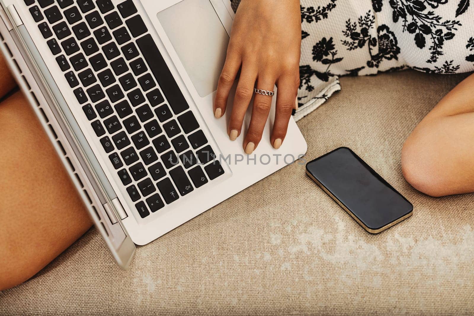 Woman relaxing on a sofa, using a laptop for work at home, showcasing a modern lifestyle of balance between productivity and downtime