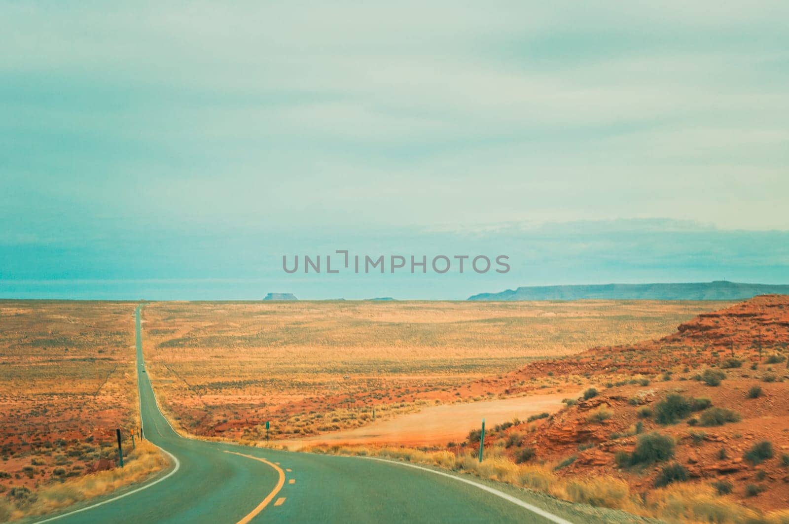 Lonely and deserted american winding road into the desert of monument valley of Arizona with vanishing point.