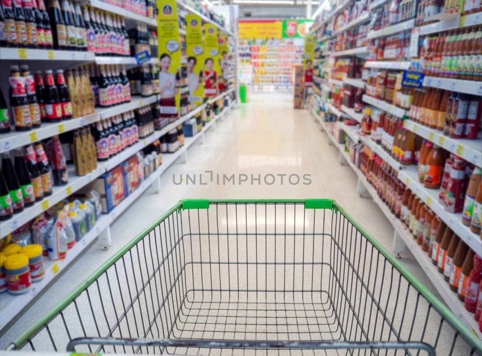 Shopping cart in supermarket, Trolley in department store Abstract blurred of colorful shelves, Empty red shopping cart view with warm light.