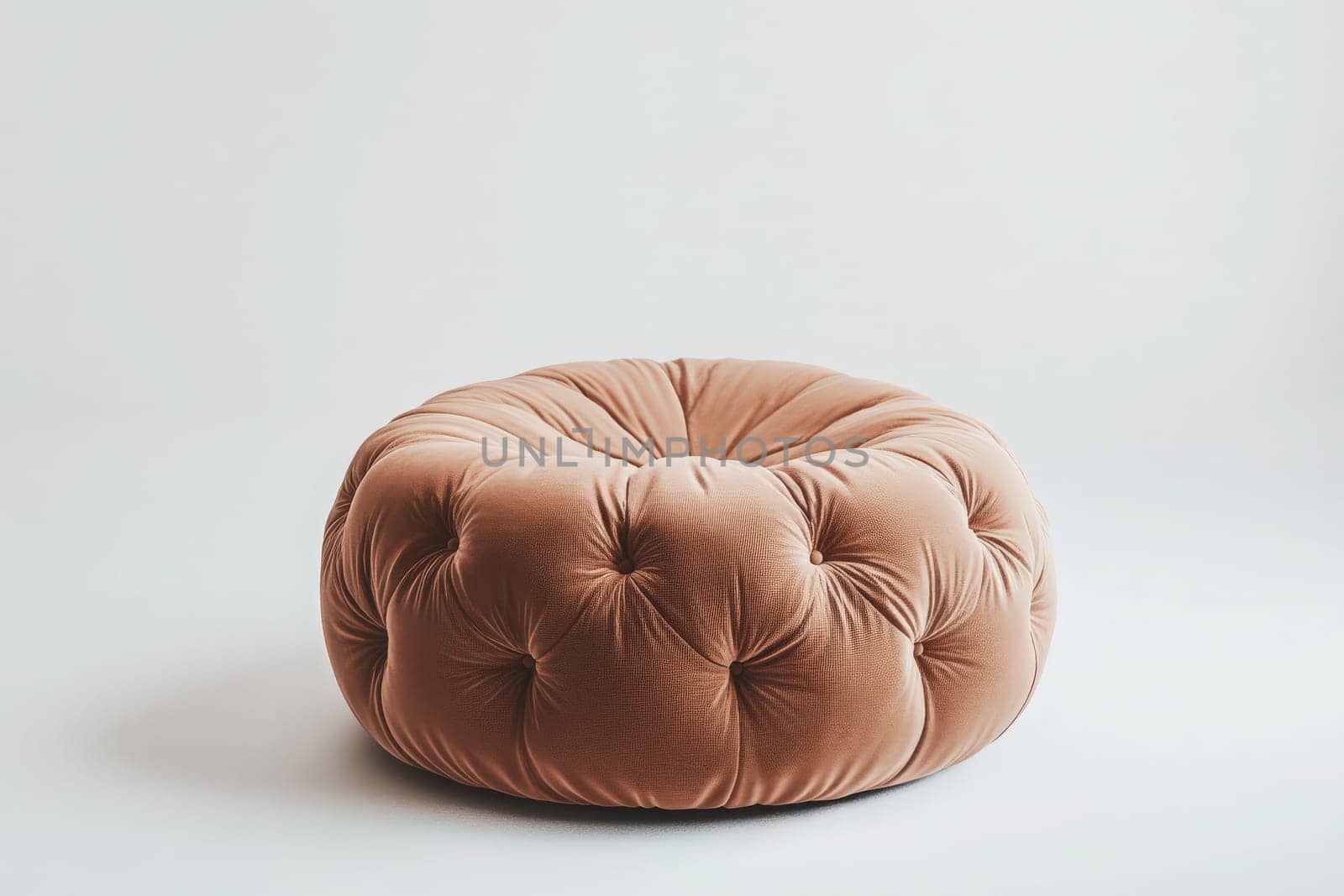 A soft, plush ottoman sits alone at the center of a minimalistic room, offering a warm touch and comfort to the inviting atmosphere. Its tufted design adds an elegant flair to the decor.