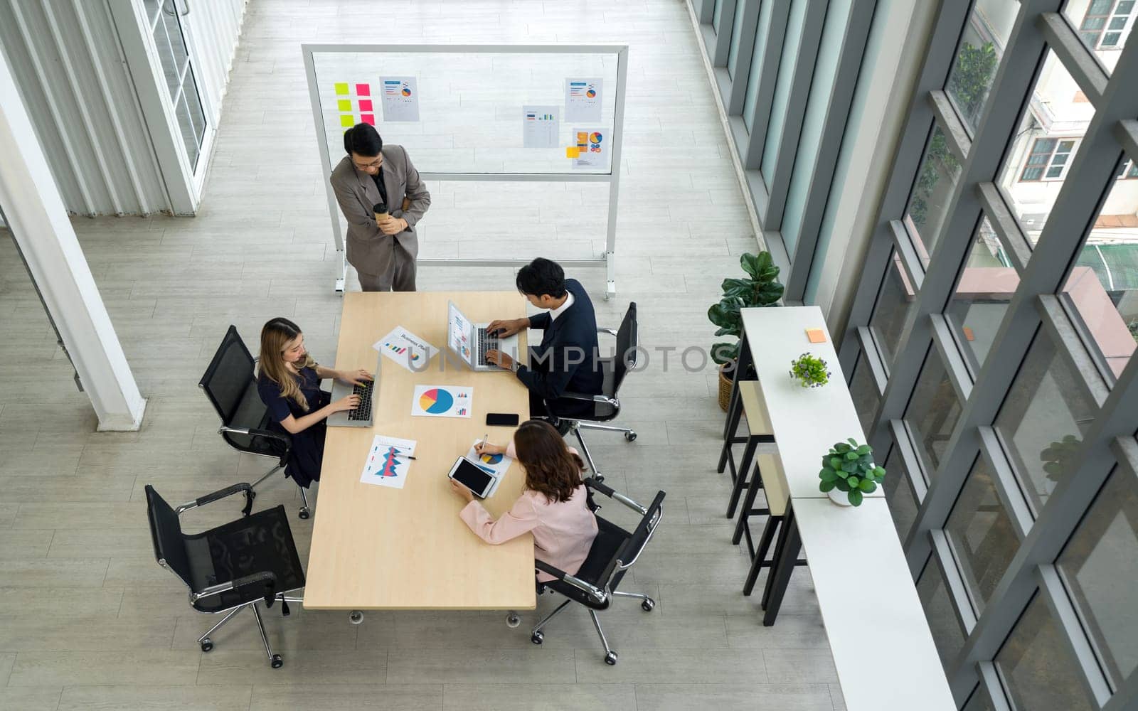 Group of business people are gathered in a meeting room, discussing and sharing ideas around a large conference table.