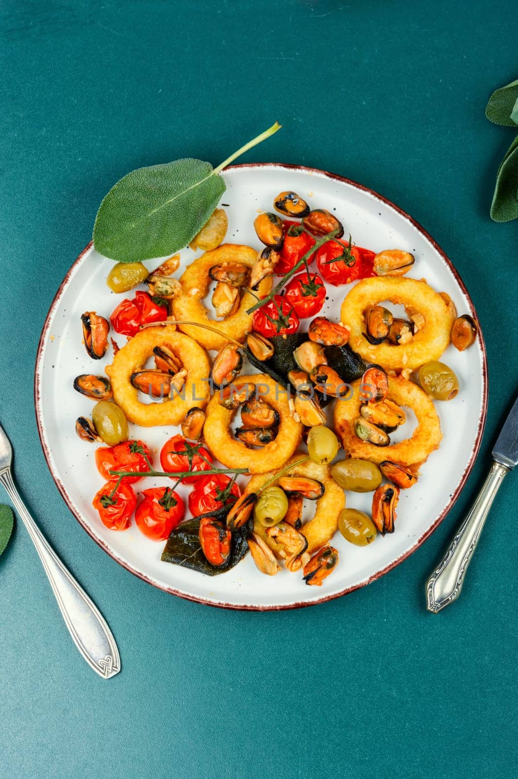 Gourmet steamed mussels with sage herb and deep fried squid rings. Roasted mixed seafood.