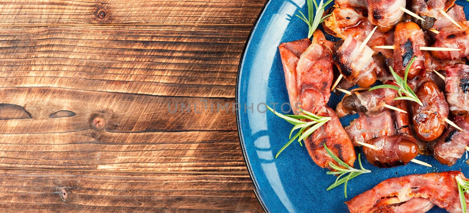 Bacon wrapped date skewers placed, English traditional snack on rustic wooden table. Space for text.