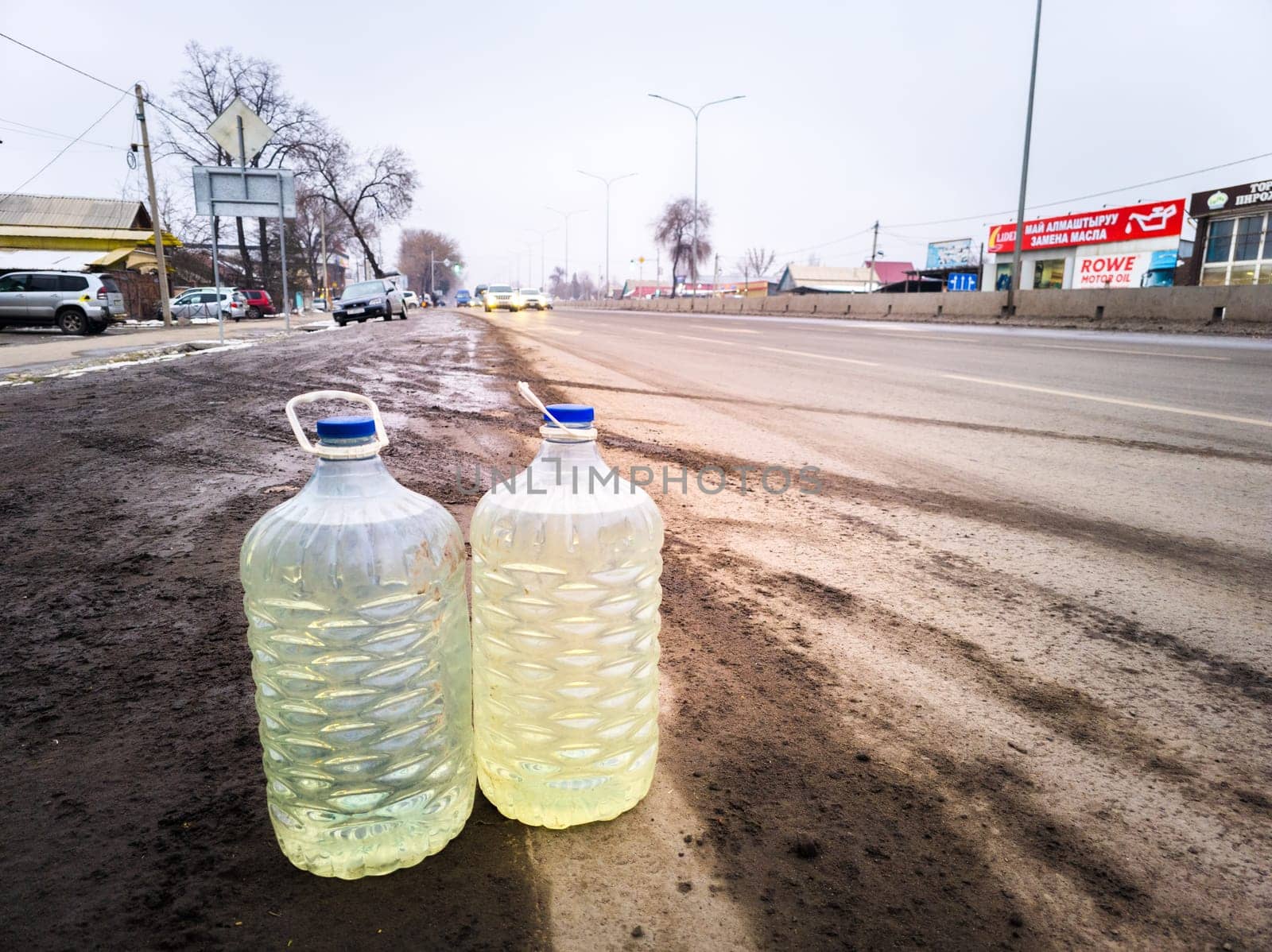 cars passing by plastic bottles with gasoline on the side of the road, the concept of street cheaper Kazakh gasoline vendors reselling in Bishkek, Kyrgyzstan - February 22, 2024