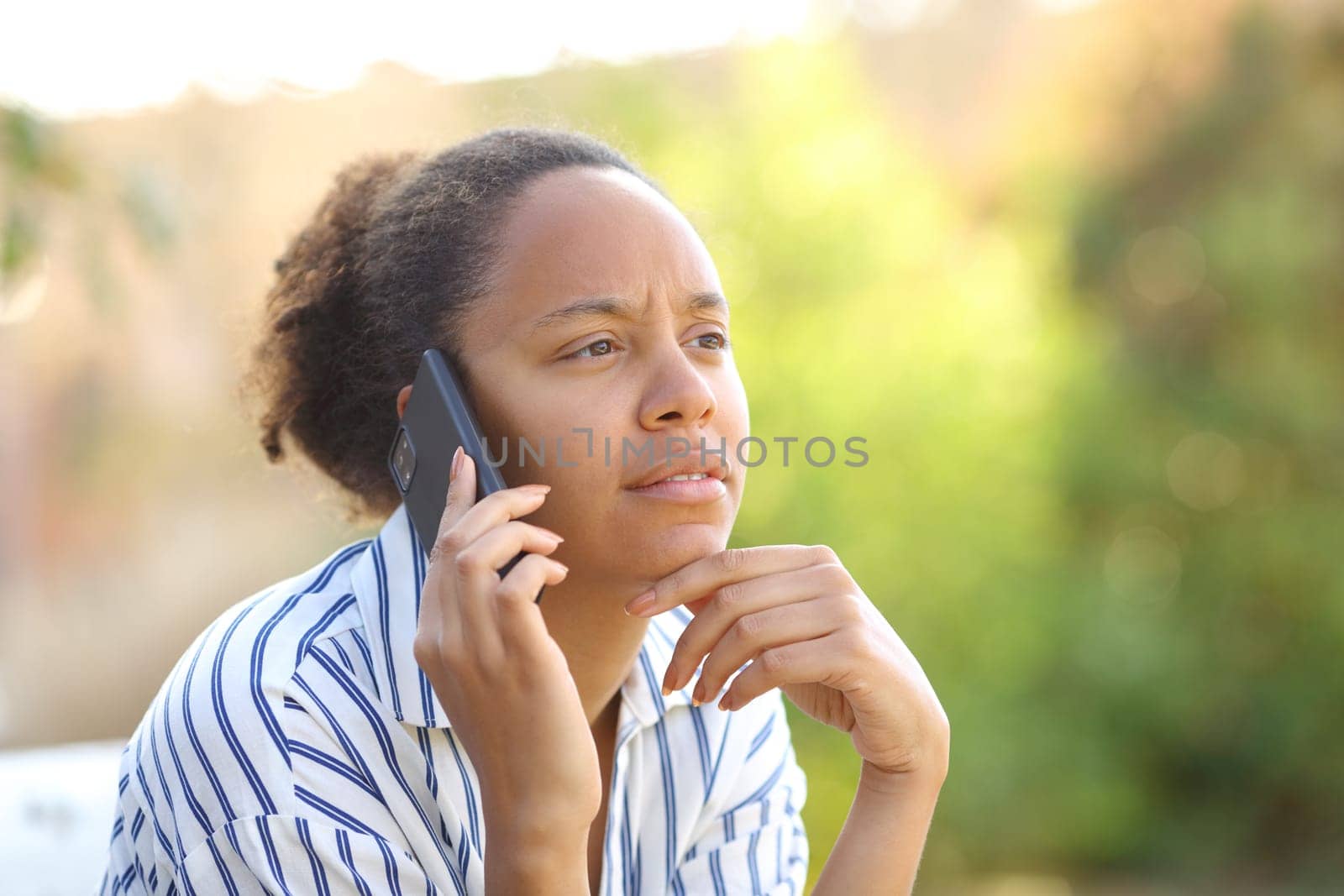 Suspicious black woman calling on phone in a park