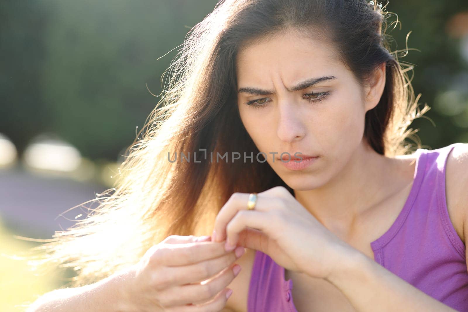 Worried fiancee looking at engagement ring in a park