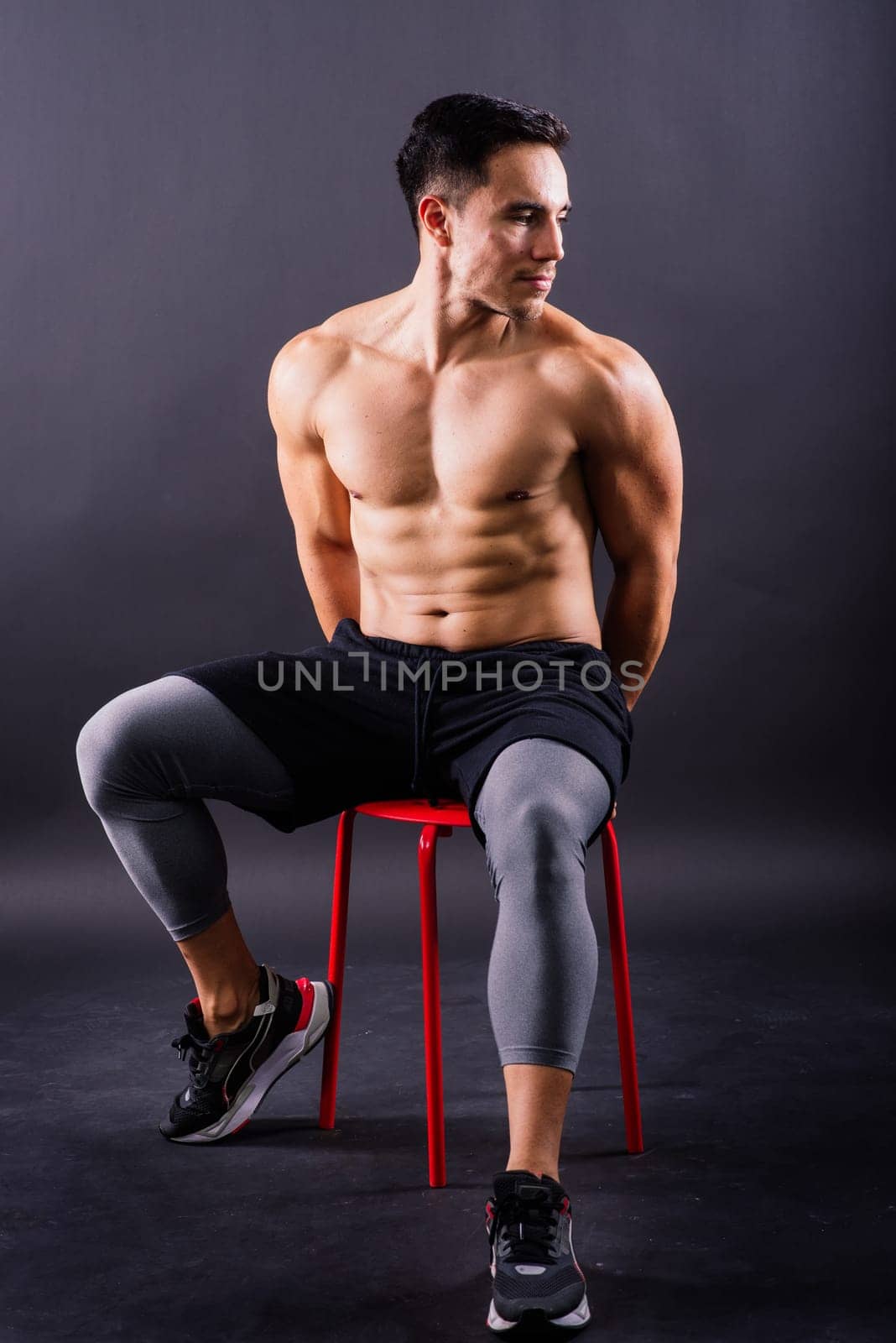 Muscular shirtless young man standing confident, front view, looking at a camera