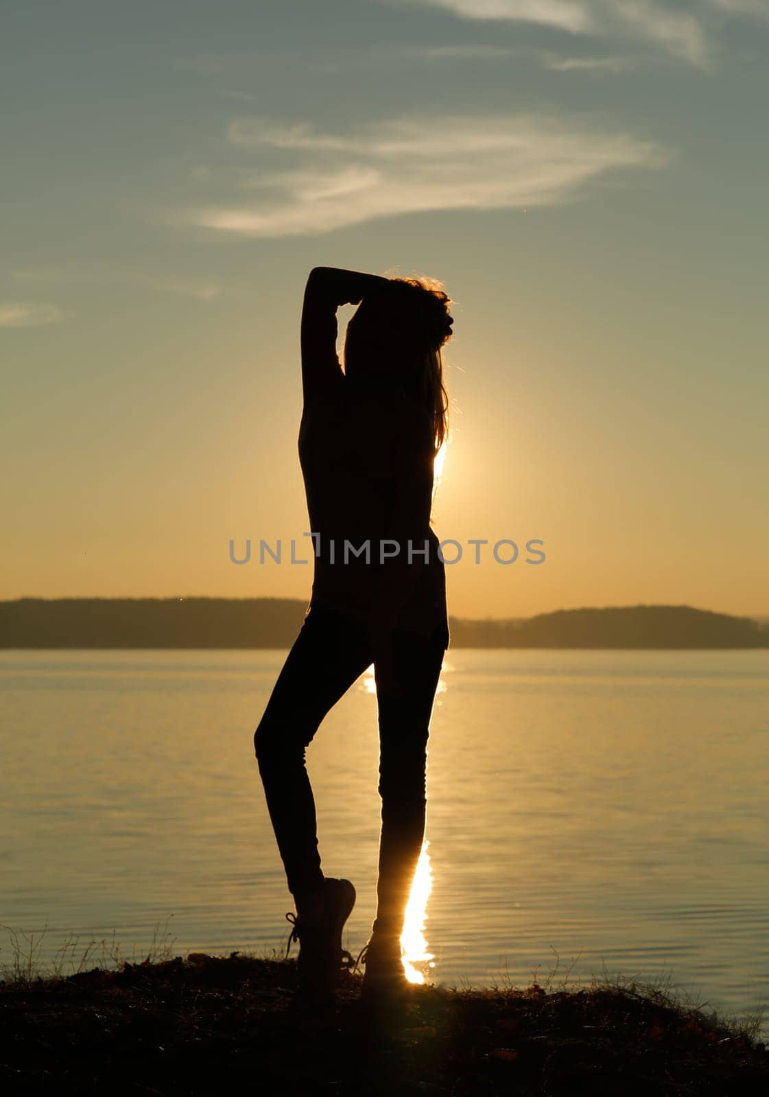 A woman stands tall, creating a striking silhouette amid the breathtaking hues of a beautiful sunset sky