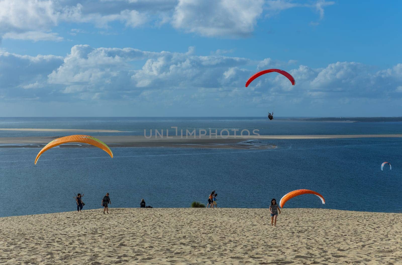 Dune of Pilat, France - August 14, 2024: People paragliding at the Great Dune of Pilat, Arcachon Basin, Nouvelle Aquitaine, France.