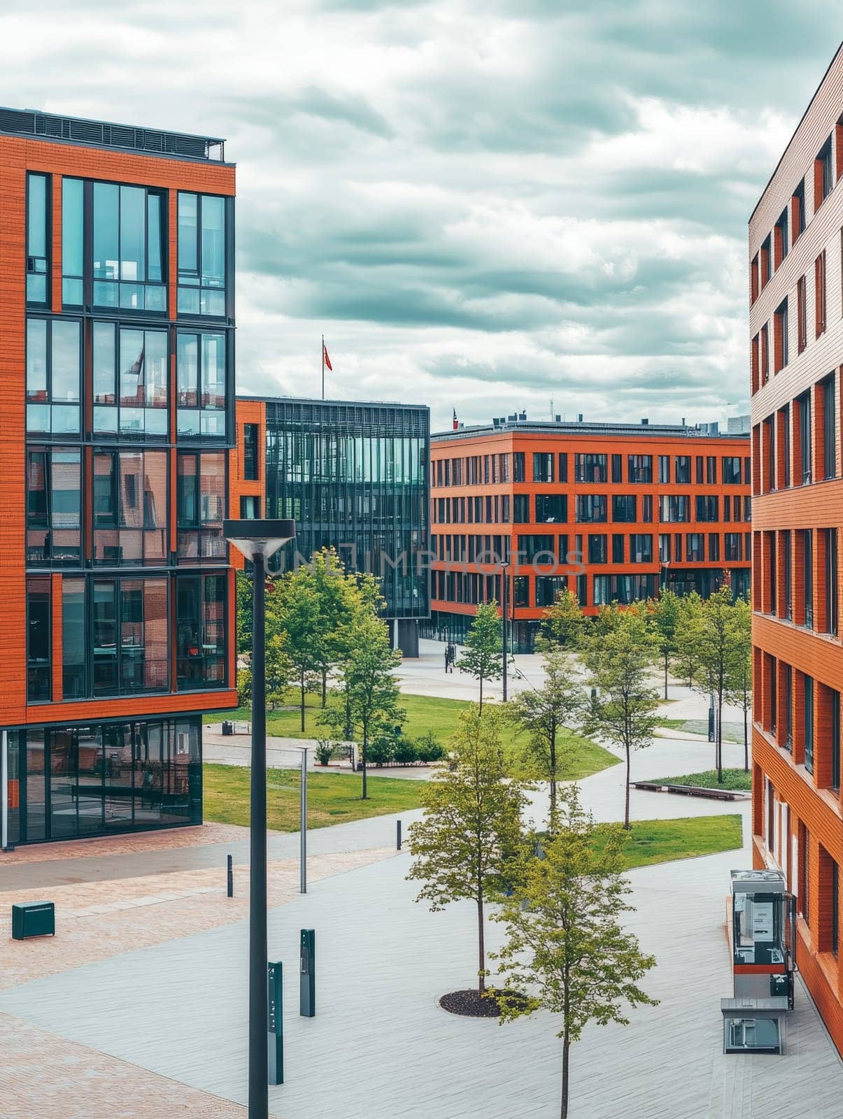 A contemporary urban campus with striking orange buildings, glass facades, and green spaces, showcasing modern architecture and sustainable design under a cloudy sky.