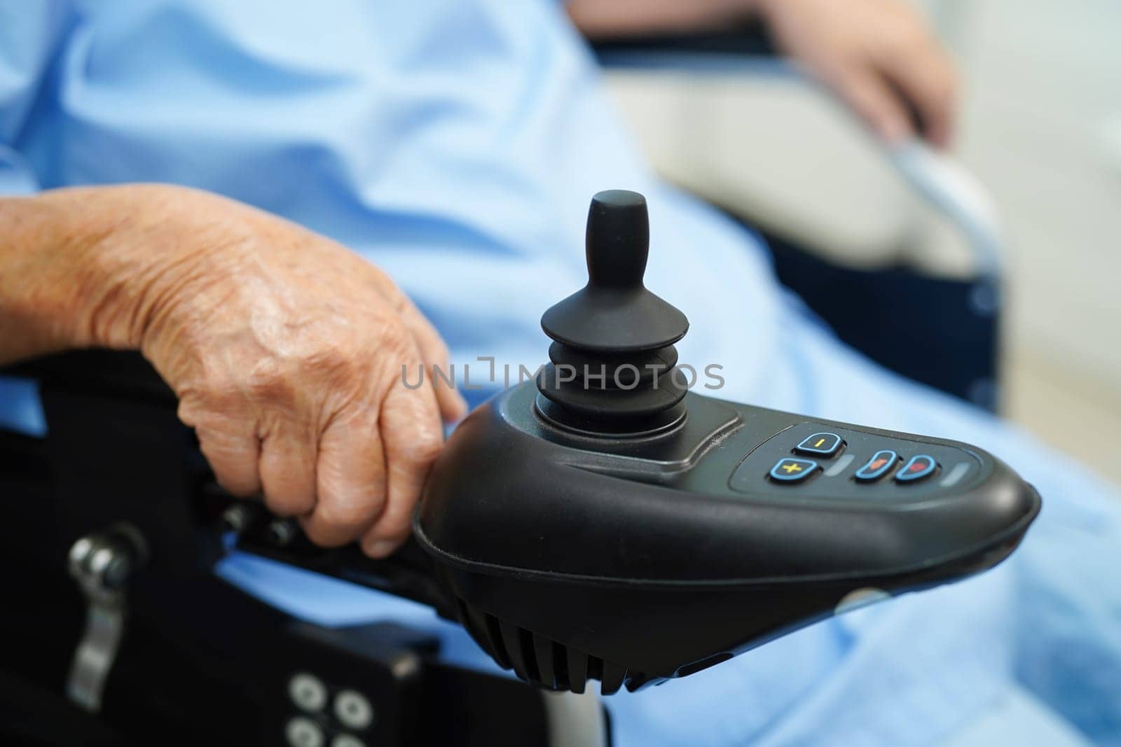 Asian elderly disability woman patient use joystick electric wheelchair in hospital.