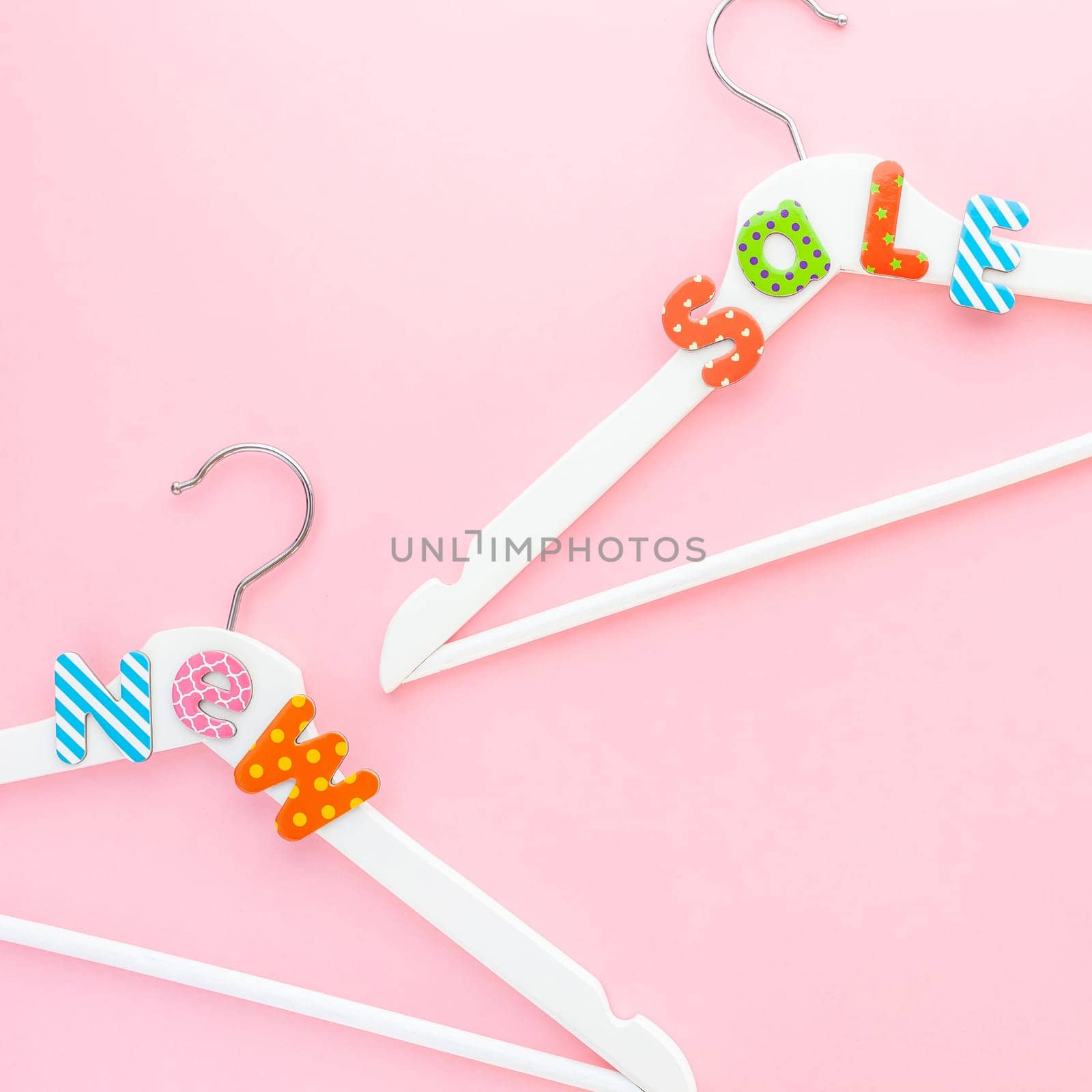 Creative top view flat lay white wooden hangers sale text pastel pink background copy space minimalism style. Template fashion feminine social media sale children store promo design shopping concept