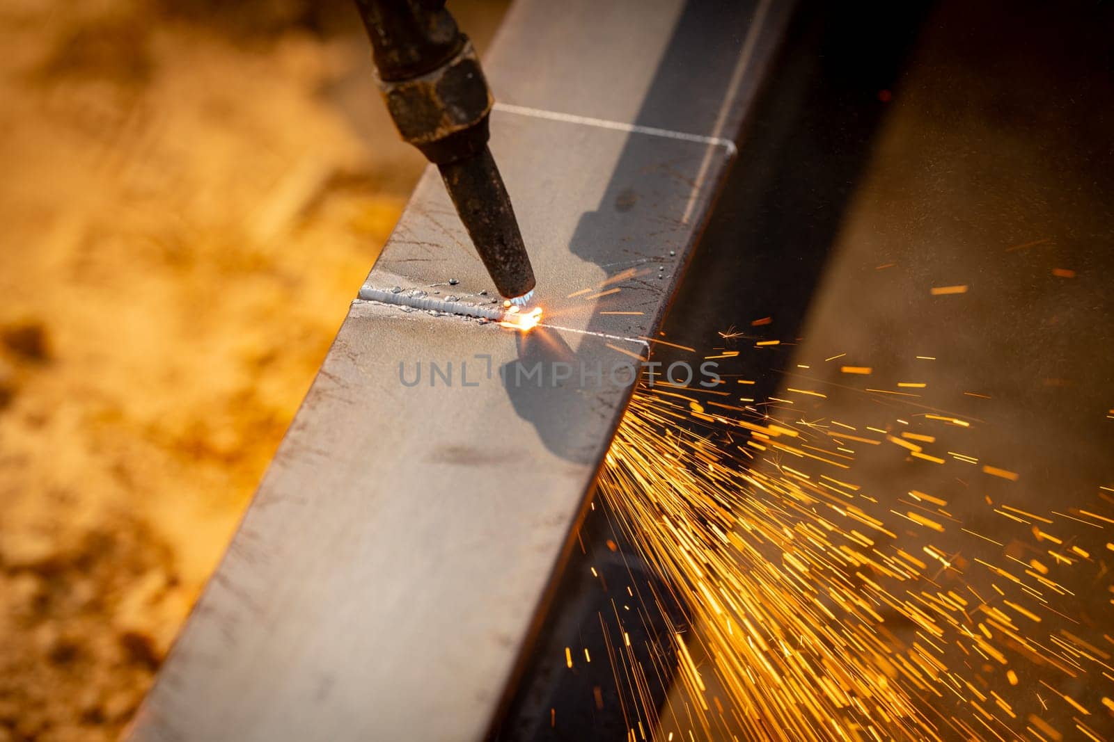 Skilled welder cuts metal with a gas torch in industrial workshop. Sparks fly during precision fabrication process. Craftsman control and expertise in metalworking. Gas torch cuts through steel.