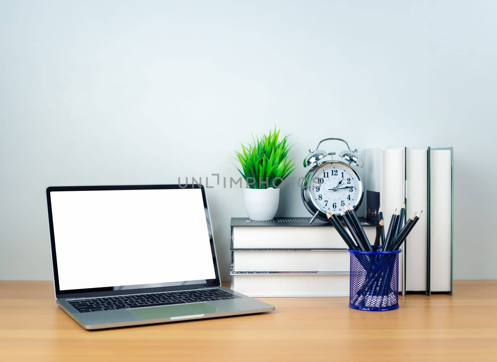 Laptop with blank screen on white table and office supplies on wooden background. Space for copying your text. Workspace and copy space. Desk with office supplies.