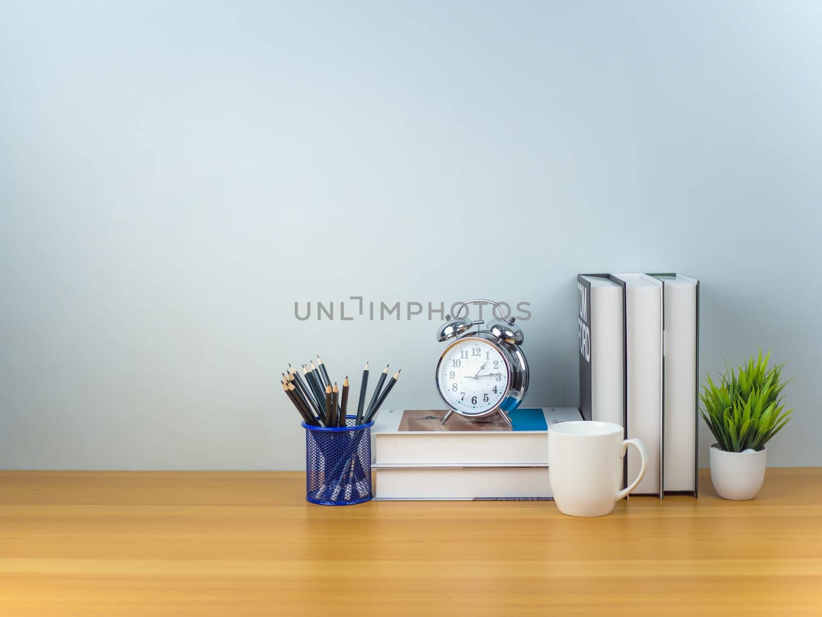 Workspace mock up white table top with Coffee cup, Pencils, Book, Alarm clock and green houseplant,Copy space desk with copy space for products display montage, Minimalist workplace with supplies.