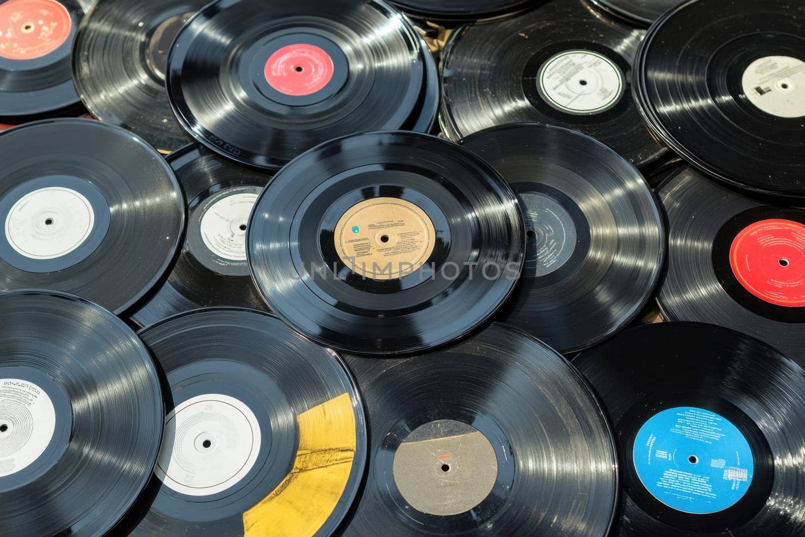 A collection of vintage vinyl records lies randomly on a wooden surface showcasing a variety of colors and labels under natural light.