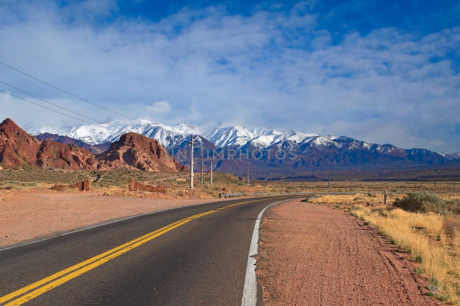 Asphalt road across the desert steppes by the Andes mountains near Uspallata, Argentina.