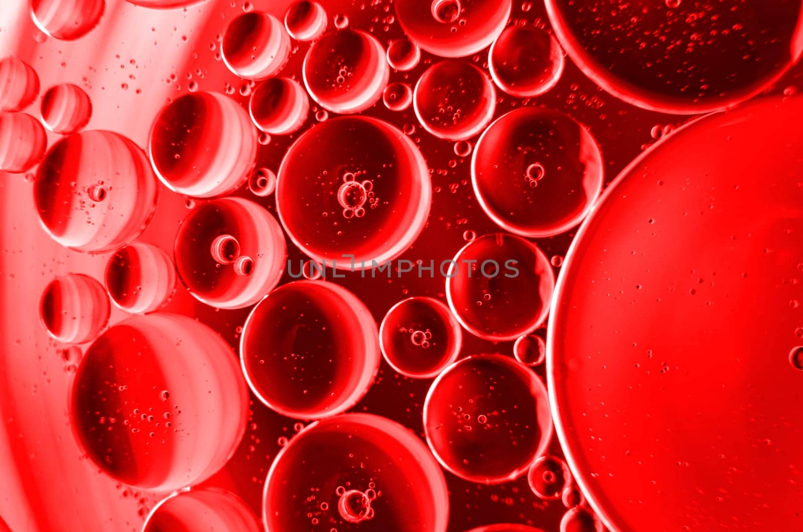 Extreme close up of oil bubbles on water surface with dark red color background. Suitable for wallpaper design